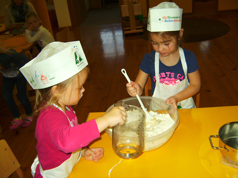 Leni und Anna vom Ramsauer Kindergarten bereiten einen Teig für Weckerl zu.